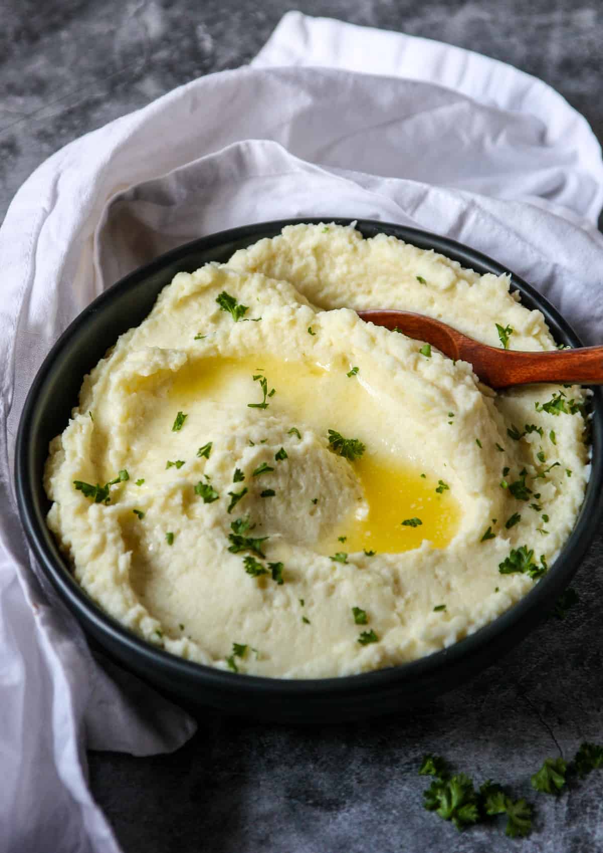Parsnip puree in a black bowl, topped with melted butter.