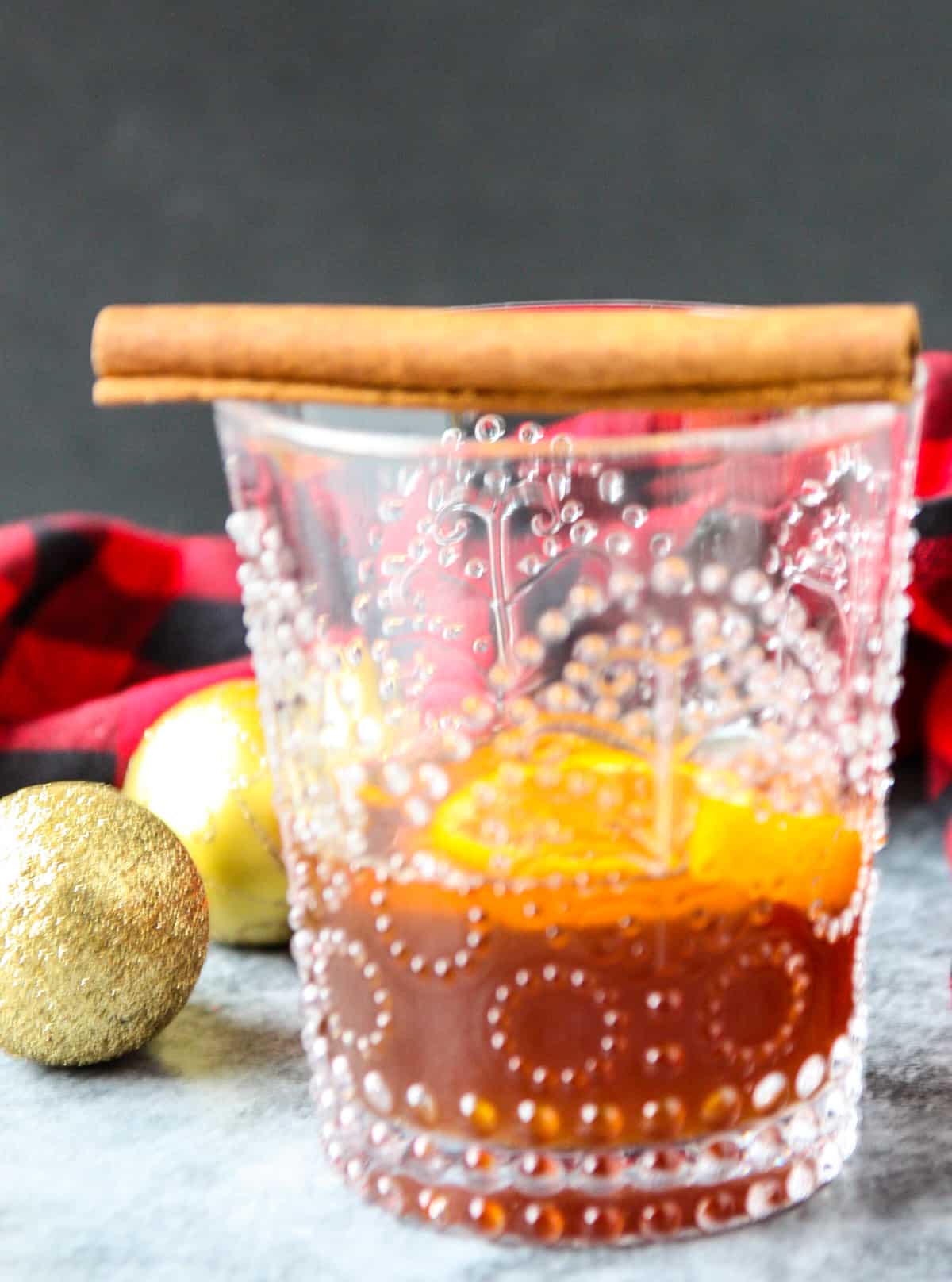 A gingerbread old fashioned cocktail in a glass topped with a cinnamon stick.