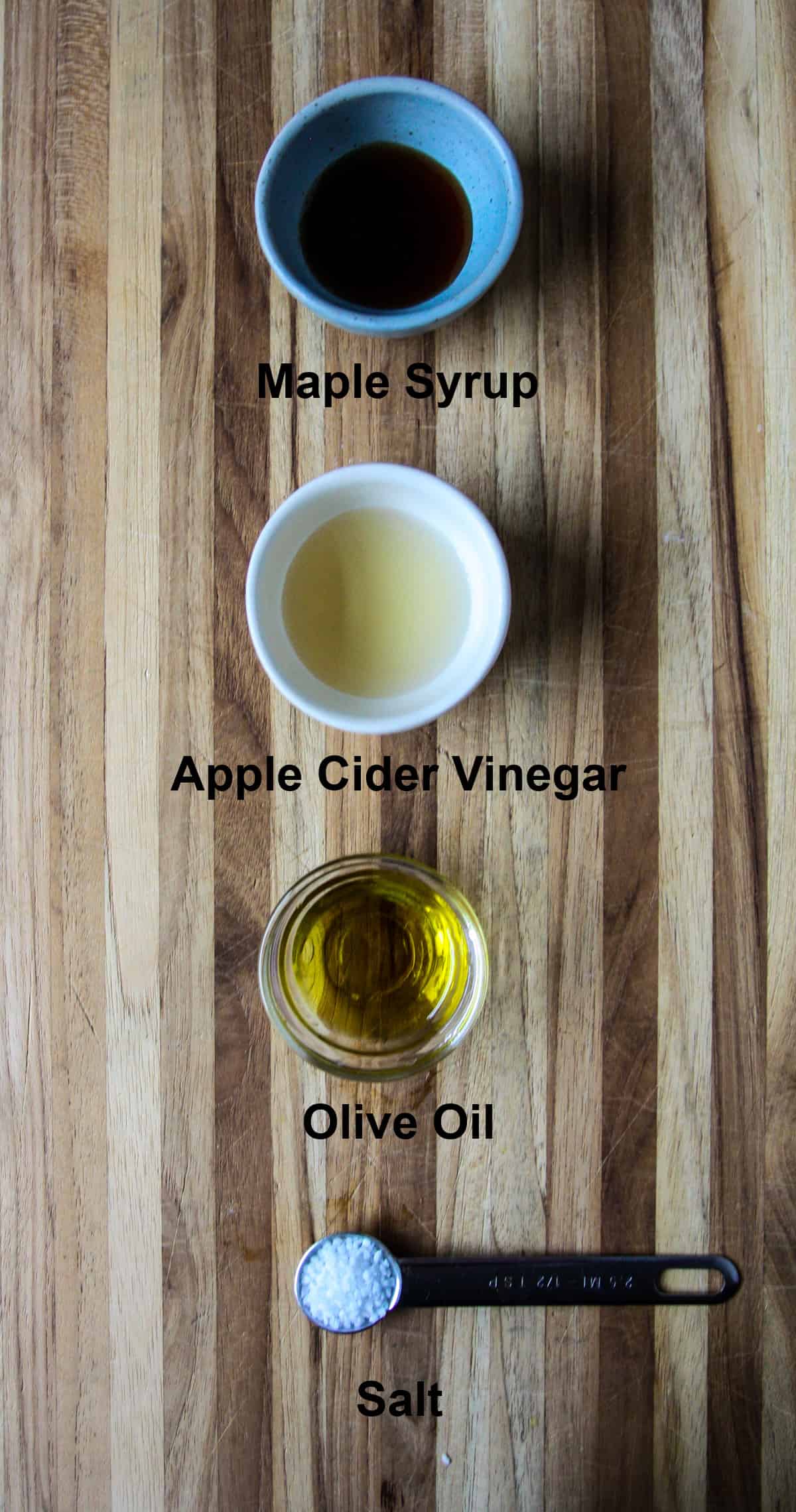 The ingredients for making the dressing, in small dishes on a wooden board.