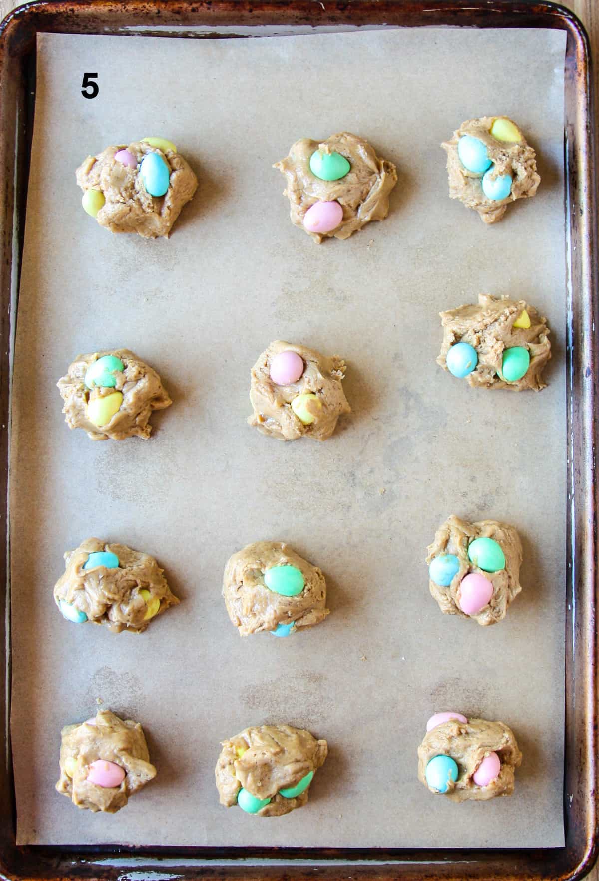 Unbaked cookie dough balls on a parchment lined baking sheet.