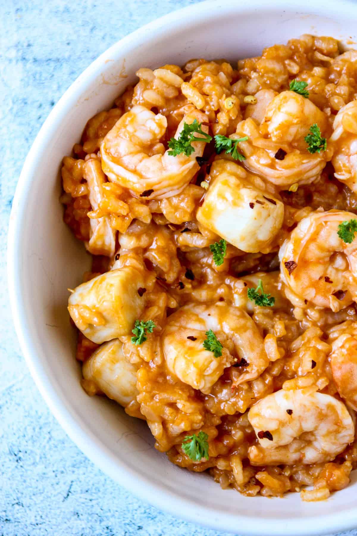 Risotto marinara with shrimp and scallops in a white bowl.
