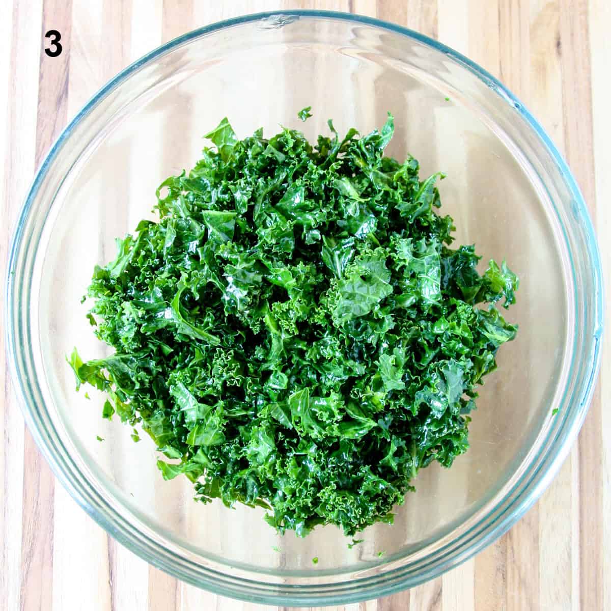 Massaged kale leaves in a glass bowl.