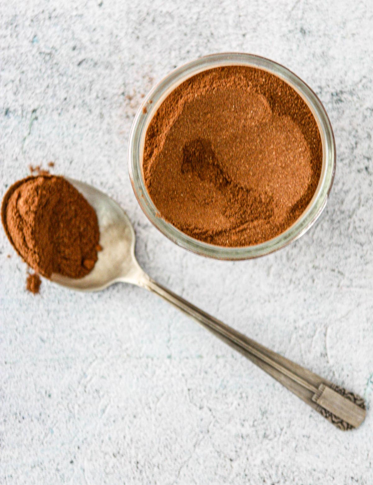 A spoonful of homemade pumpkin pie spice on a white countertop.