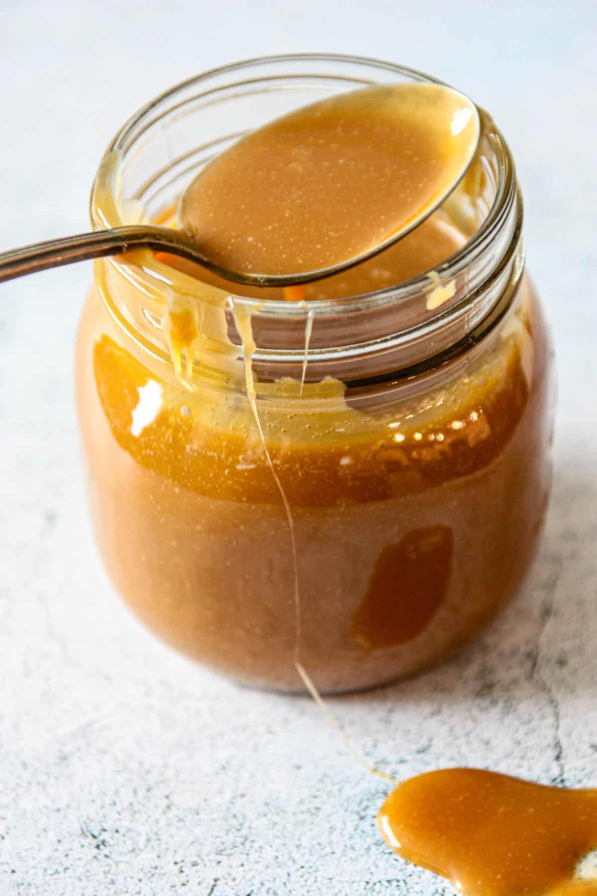 A jar of caramel sauce with a little spilled on the counter.