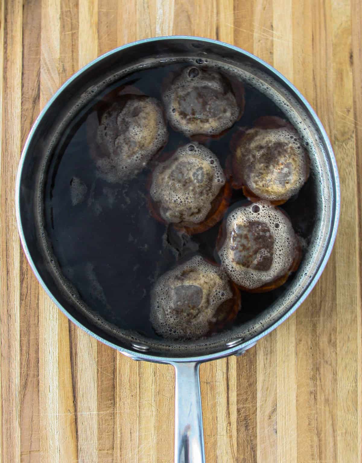 Teabags steeping in a saucepan full of water.