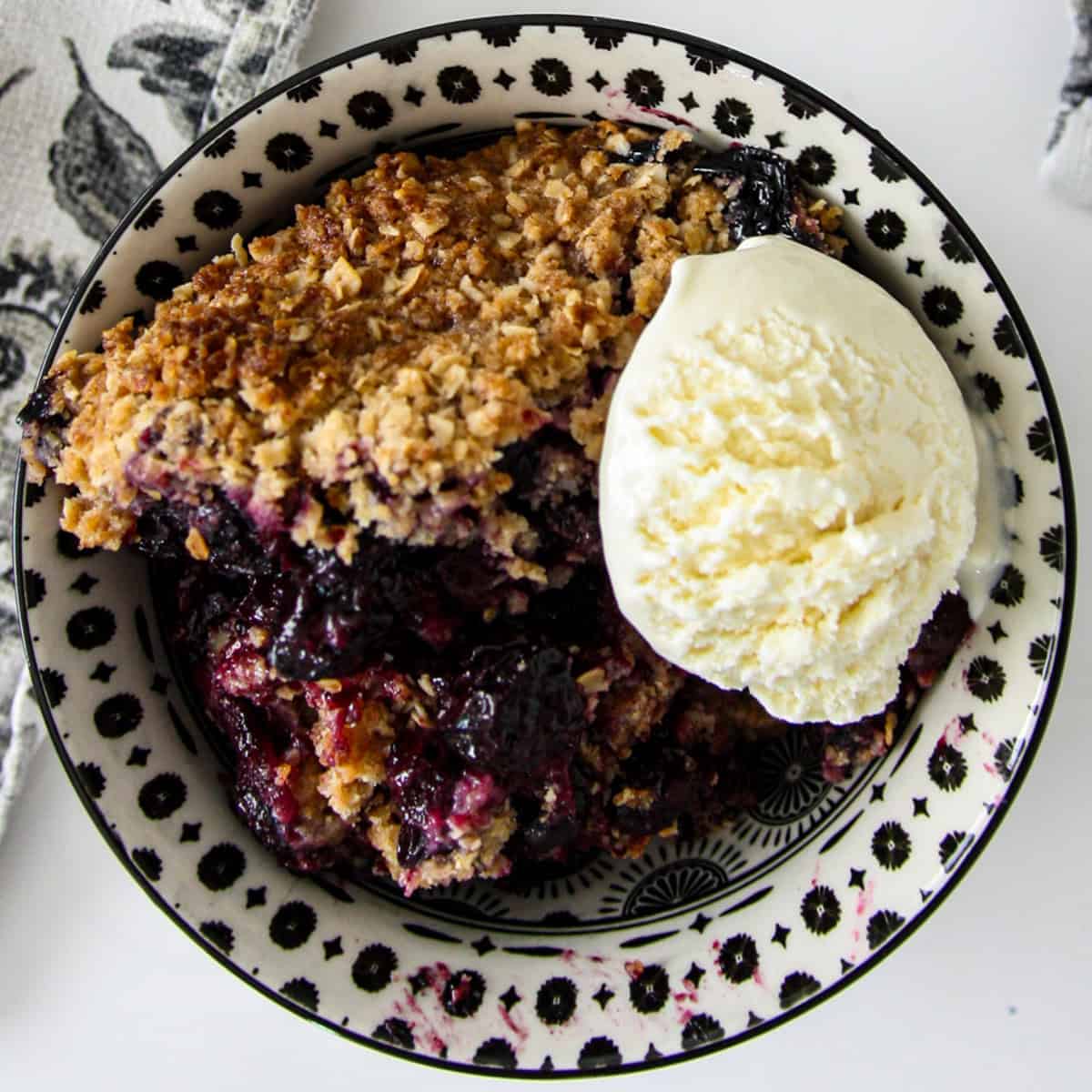 Gluten-free blueberry crisp in a black and white bowl.