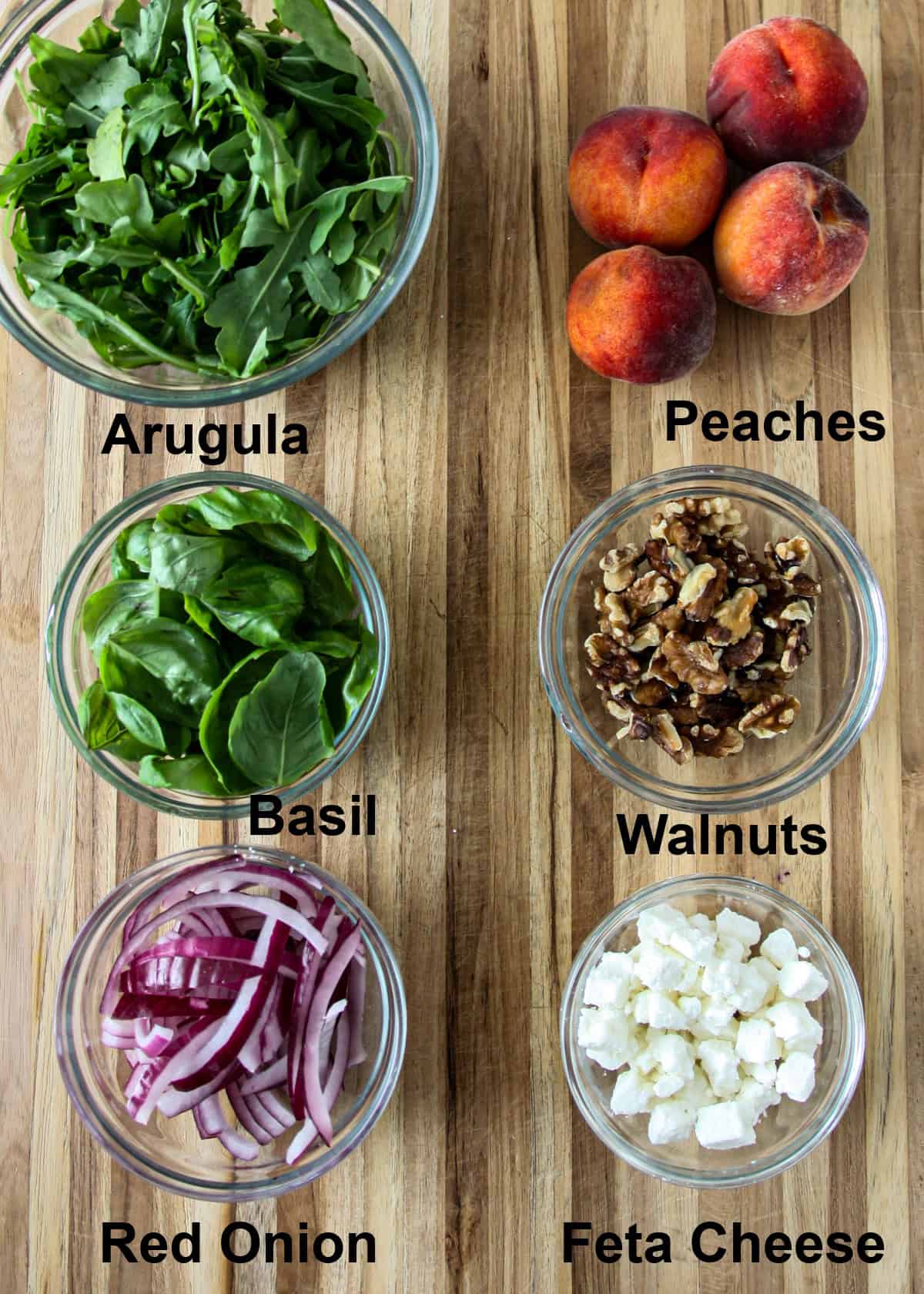 The ingredients for the salad in glass bowls on a wooden board.